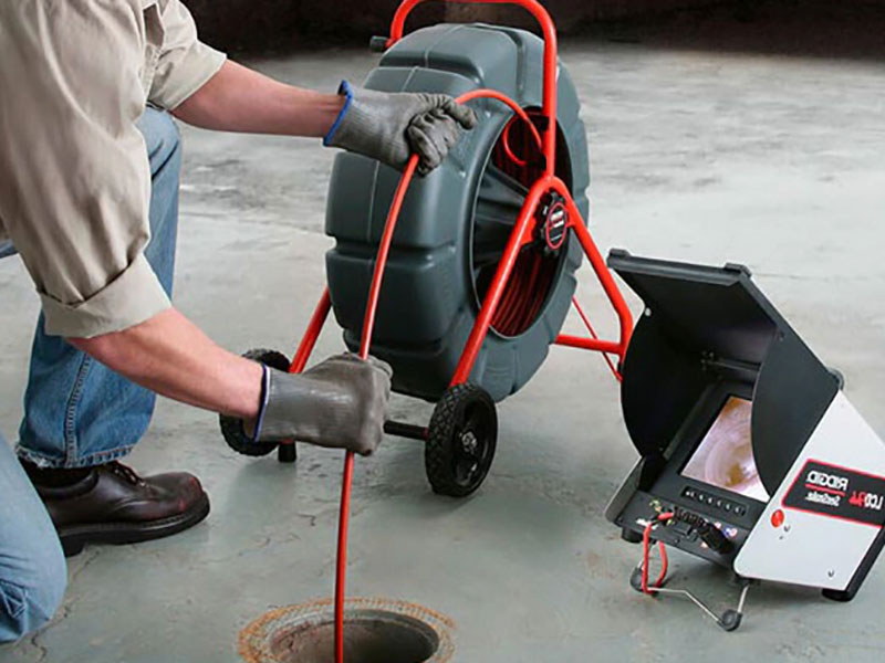 man inspecting sewer line with camera